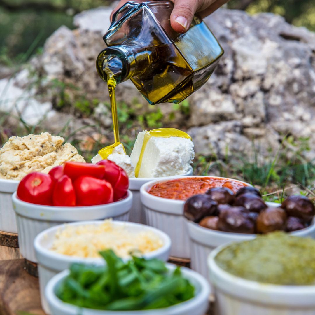 Mediterranean-style meal of roasted vegetables, lentils, oily fish and olive oil beside a glass of water and a pair of walking shoes, illustrating everyday habits for liver health.